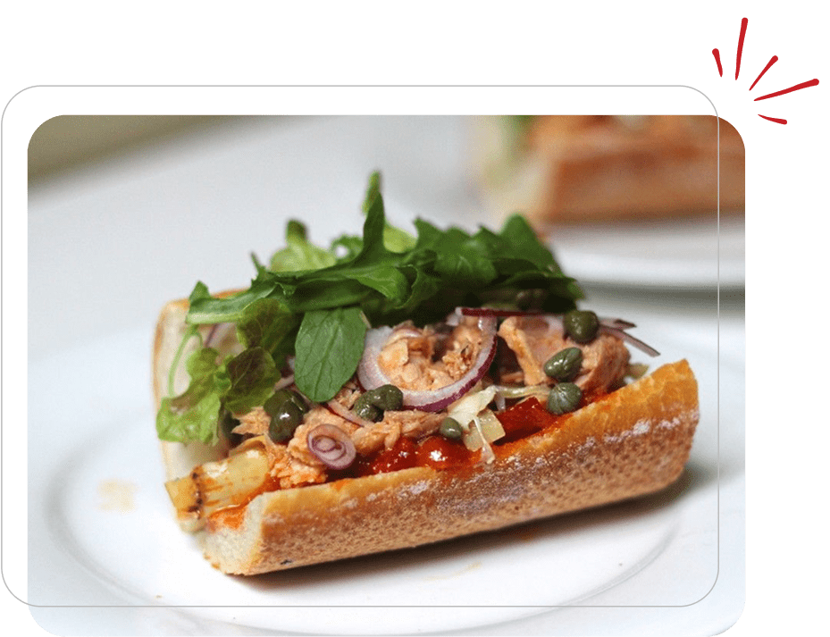 Sandwich with greens and capers on plate.