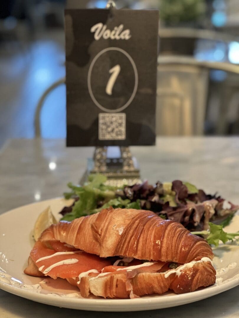 Croissant sandwich with salad on plate.