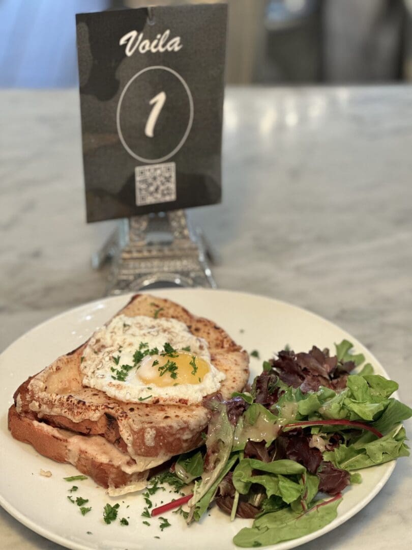 Croque madame with salad on marble table.